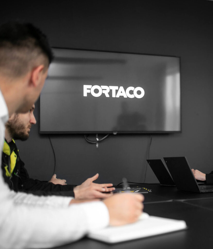 A group of people sitting around a table in front of a tv.
