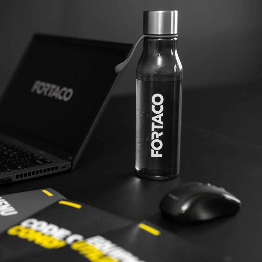 A bottle of water next to a laptop and a mouse.