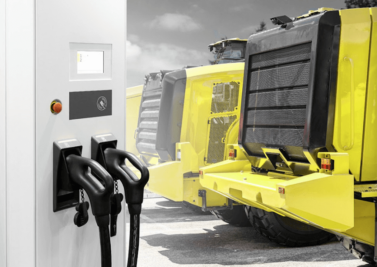 A yellow truck is parked next to a charging station.
